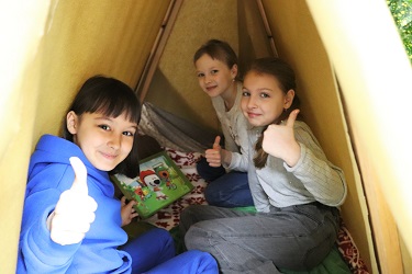 Девочки в палатке показывают знак "Класс"